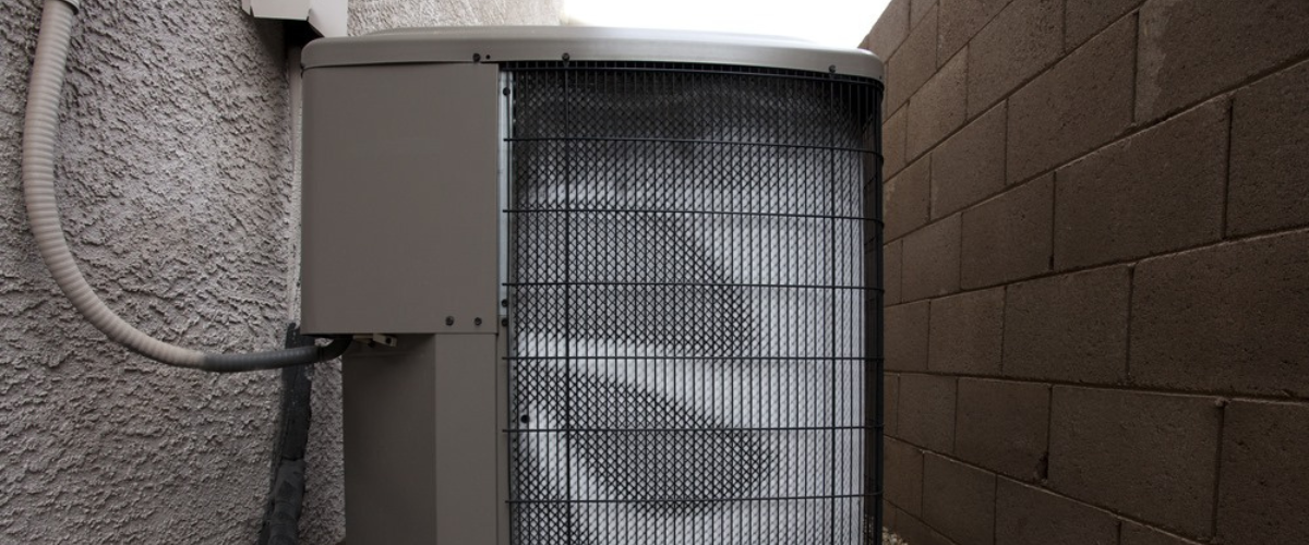An outdoor heating unit in an alley of a house between off white walls